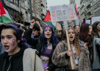 Manifestación feminista en una ciudad con jóvenes protestando, pancartas reivindicativas y símbolos de igualdad en el rostro