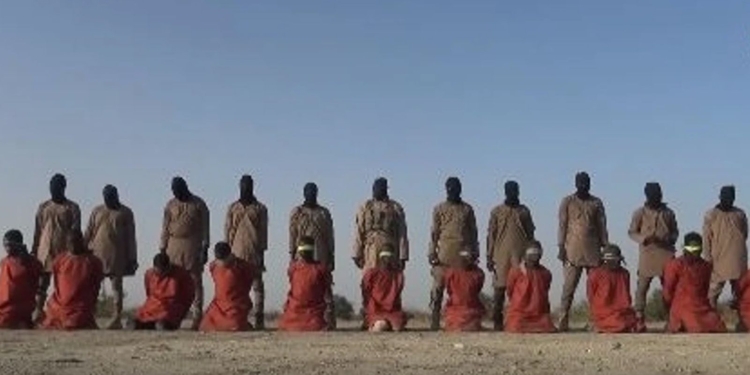 Grupo de hombres vestidos de naranja arrodillados frente a individuos armados en un entorno desértico, escena asociada a propaganda terrorista.
