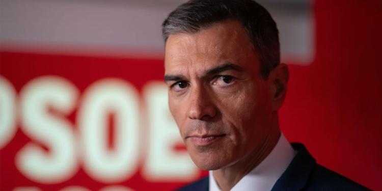 Pedro Sánchez en primer plano con fondo rojo del PSOE durante un acto político.