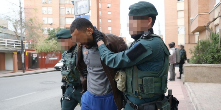 Agentes de la Guardia Civil deteniendo a un hombre en la vía pública en un entorno urbano.