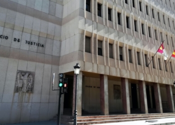 Fachada de un edificio institucional con el rótulo “Palacio de Justicia”, con varias banderas oficiales en la entrada y un semáforo peatonal en primer plano.