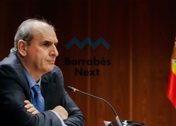 Juan Carlos Barrabés en un micrófono en una sala institucional, con el logo de Barrabés Next y la bandera de España al fondo.