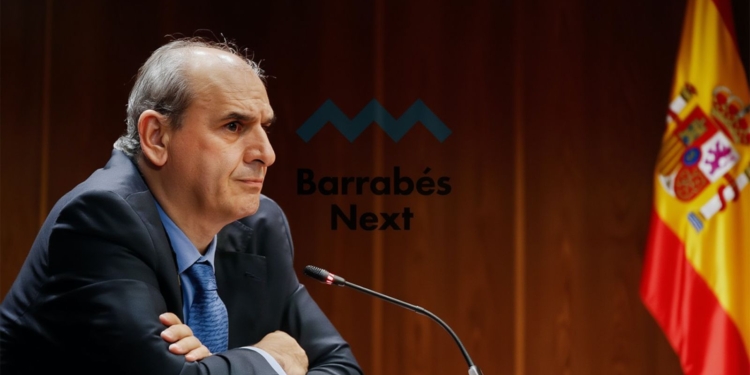 Juan Carlos Barrabés en un micrófono en una sala institucional, con el logo de Barrabés Next y la bandera de España al fondo.