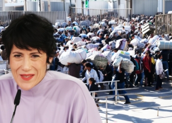 Montaje con Elma Saiz hablando en un micrófono en primer plano y, de fondo, una gran multitud de personas inmigrantes cargando bultos en una zona fronteriza.