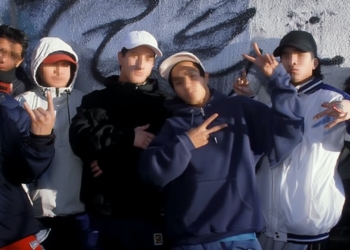 Grupo de jóvenes con el rostro pixelado posando juntos frente a un muro con grafitis, haciendo gestos con las manos y vistiendo ropa urbana.