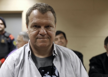 Joan Vila Dilmé conocido como el Asesino de Olot, en primer plano dentro de una sala judicial, con varias personas sentadas detrás y un agente uniformado al fondo.