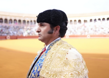 El Torero Jose Antonio Morante de la Puebla vestido con traje de luces y montera, de perfil en una plaza de toros llena de público al fondo.