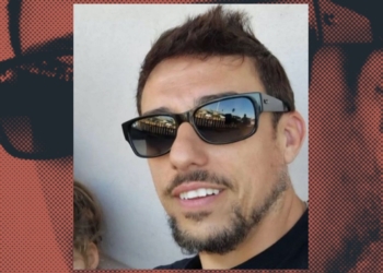 Primer plano de Vicente L. G con barba corta y gafas de sol oscuras, sonriendo ligeramente; el fondo incluye un diseño gráfico con su rostro repetido en tonos rojizos.