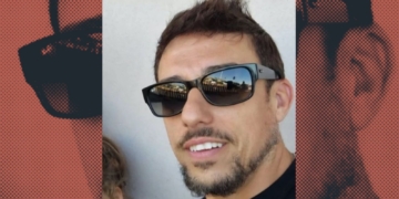 Primer plano de Vicente L. G con barba corta y gafas de sol oscuras, sonriendo ligeramente; el fondo incluye un diseño gráfico con su rostro repetido en tonos rojizos.