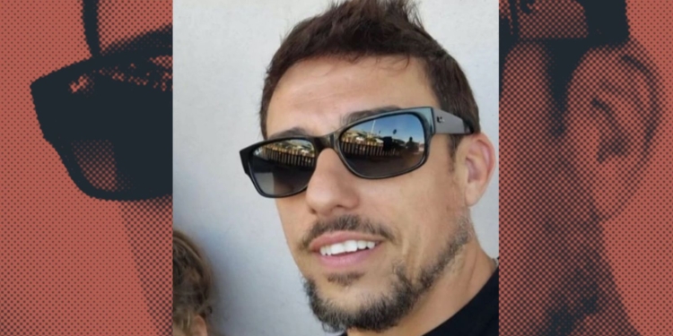 Primer plano de Vicente L. G con barba corta y gafas de sol oscuras, sonriendo ligeramente; el fondo incluye un diseño gráfico con su rostro repetido en tonos rojizos.