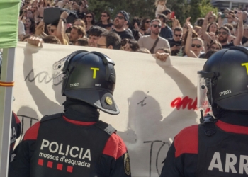 Agentes de los Mossos d’Esquadra con casco antidisturbios frente a una multitud de manifestantes.