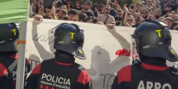 Agentes de los Mossos d’Esquadra con casco antidisturbios frente a una multitud de manifestantes.