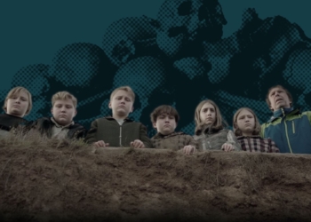 Un grupo de niños y un adulto observan hacia abajo desde el borde de un terreno elevado.