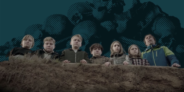 Un grupo de niños y un adulto observan hacia abajo desde el borde de un terreno elevado.