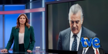 Presentadora en un plató de televisión junto a una pantalla donde aparece Bárcenas trajeado