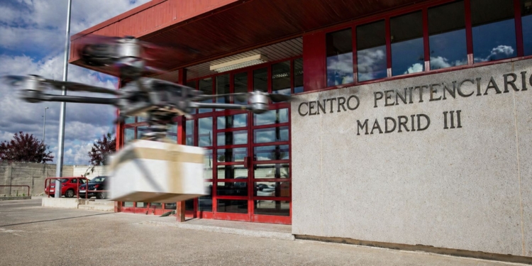Entrada del Centro Penitenciario Madrid III con un dron volando en primer plano transportando un paquete.