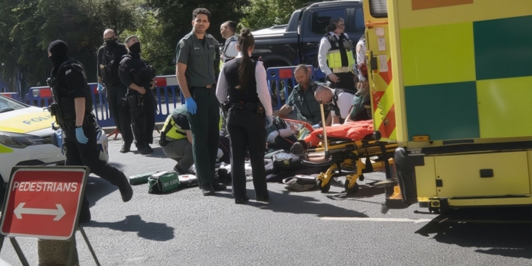 Agentes de policía y sanitarios atienden a una persona herida en la calle junto a una ambulancia.
