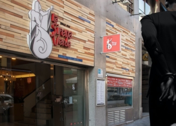 Fachada de un restaurante en una calle urbana con una figura humana esposada en primer plano.