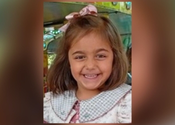 ¿Dónde está Miranda? Niña pequeña sonriente con lazo en el cabello, en lo que parece un entorno de juego o parque