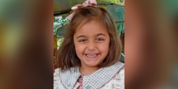 ¿Dónde está Miranda? Niña pequeña sonriente con lazo en el cabello, en lo que parece un entorno de juego o parque