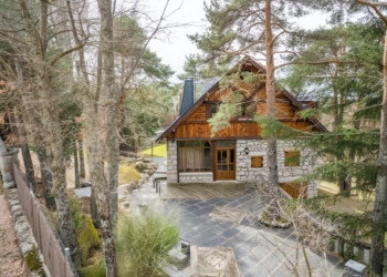 Casa de Mónica García de estilo rústico construida en piedra y madera en medio de un bosque de pinos.