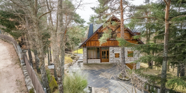 Casa de Mónica García de estilo rústico construida en piedra y madera en medio de un bosque de pinos.