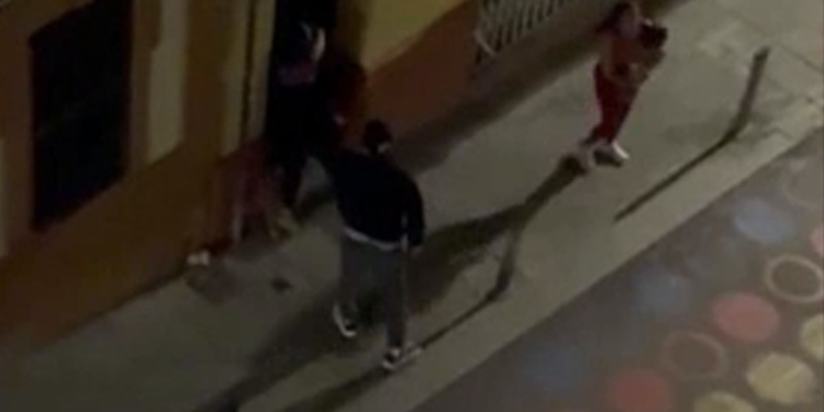 Imagen nocturna de varias personas en una acera captada desde una cámara de vigilancia o gran altura en España