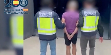 Cambio de género: Dos agentes de la Policía Nacional escoltan a una persona detenida con las manos esposadas detrás de la espalda.