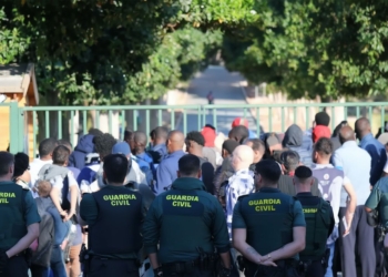 70 inmigrantes se amotinan en un centro de Alicante y Agentes de la Guardia Civil observan a un grupo numeroso de personas frente a una entrada.