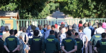 70 inmigrantes se amotinan en un centro de Alicante y Agentes de la Guardia Civil observan a un grupo numeroso de personas frente a una entrada.