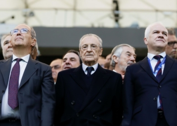 Florentino Pérez en el Bernabéu con varios directivos y asistentes vestidos de traje observan un evento desde la grada.