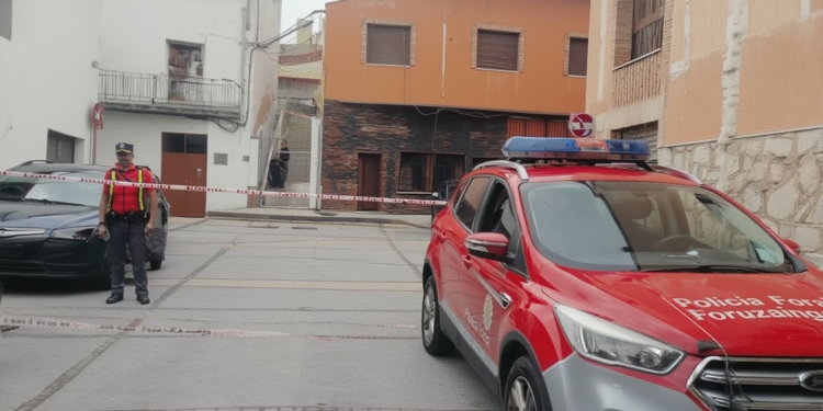 Navarra: magrebí confiesa el asesinato de su mujer . Calle acordonada por la policía con un vehículo de la Policía Foral estacionado frente a varios edificios residenciales.