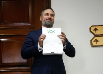 Abascal pide moción de censura tras la imputación a Zapatero. sostiene un documento con el logotipo de VOX en el interior de un edificio oficial.