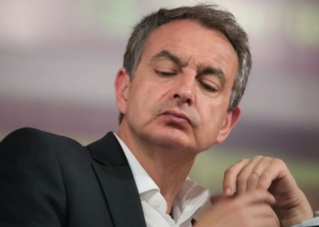 ¿Fuga a Caracas? Zapatero y su sospechoso plan de vuelo: Primer plano de Zapatero con traje oscuro y expresión seria durante un acto público.