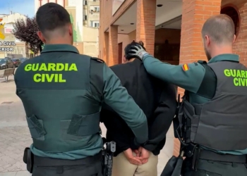 Caos total: 30 robos y el Gobierno le tramita la residencia. Dos agentes de la Guardia Civil trasladan a una persona detenida por una calle urbana.
