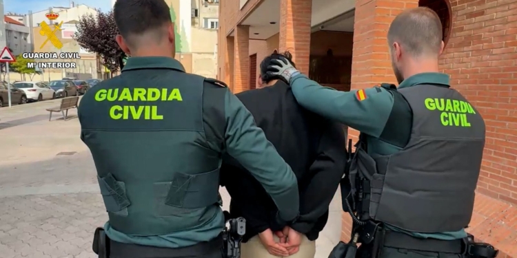 Caos total: 30 robos y el Gobierno le tramita la residencia. Dos agentes de la Guardia Civil trasladan a una persona detenida por una calle urbana.
