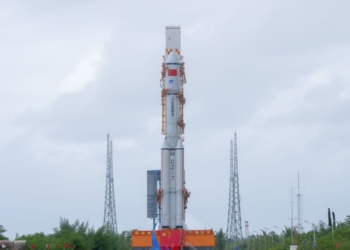 China lanza embriones humanos artificiales al espacio. cohete espacial permanece en posición vertical sobre una plataforma de lanzamiento bajo un cielo nublado.