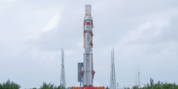 China lanza embriones humanos artificiales al espacio. cohete espacial permanece en posición vertical sobre una plataforma de lanzamiento bajo un cielo nublado.