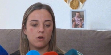 La madre de la bebé de 16 meses fallecida sospecha de que su pareja la quemó «por celos». Mamá del bebe sentada en un sofá mientras atiende a varios micrófonos durante una entrevista.