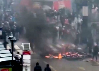 Bruselas: la ultraizquierda y los inmigrantes destrozan el corazón de Europa. Disturbios en Bruselas con barricadas en llamas y denso humo en una calle urbana.