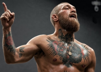 ¡Conor McGregor estalla! Exige expulsiones tras brutal intento de degollamiento en Belfast. Conor McGregor sin camiseta, con el torso tatuado, levantando el dedo índice mientras grita.