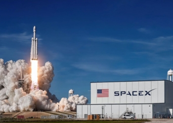 ¿Por qué Elon Musk hace ahora la salida a bolsa de SpaceX?. Lanzamiento de un cohete de SpaceX desde su base, con una gran nube de humo y fuego, junto al edificio principal de la compañía.