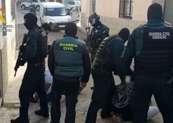 Narcos tirotean a la Guardia Civil en Punta Umbría dejando a los agentes indefensos. Agentes de la Guardia Civil, algunos con pasamontañas y equipamiento táctico, deteniendo a varias personas en el suelo durante una operación policial.