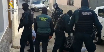 Narcos tirotean a la Guardia Civil en Punta Umbría dejando a los agentes indefensos. Agentes de la Guardia Civil, algunos con pasamontañas y equipamiento táctico, deteniendo a varias personas en el suelo durante una operación policial.