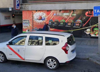 Machete en mano: persiguen y apuñalan a un taxista en Madrid. Taxi blanco aparcado frente a un salón de tragaperras o casino.