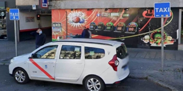 Machete en mano: persiguen y apuñalan a un taxista en Madrid. Taxi blanco aparcado frente a un salón de tragaperras o casino.