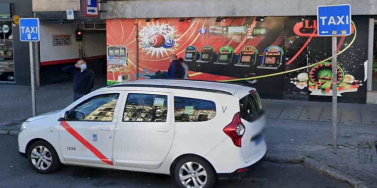 Machete en mano: persiguen y apuñalan a un taxista en Madrid. Taxi blanco aparcado frente a un salón de tragaperras o casino.