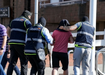 5 nuevos sucesos: la ola de "casos aislados" que sigue azotando España. Agentes de la Policía Nacional escoltando a una persona con la cabeza cubierta en la Plaza de España.