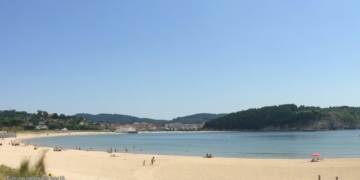 Policías acorralados por bandas en Plentzia: la calle ya no es nuestra. Playa de Plentzia con arena, mar y colinas al fondo, generada por inteligencia artificial.